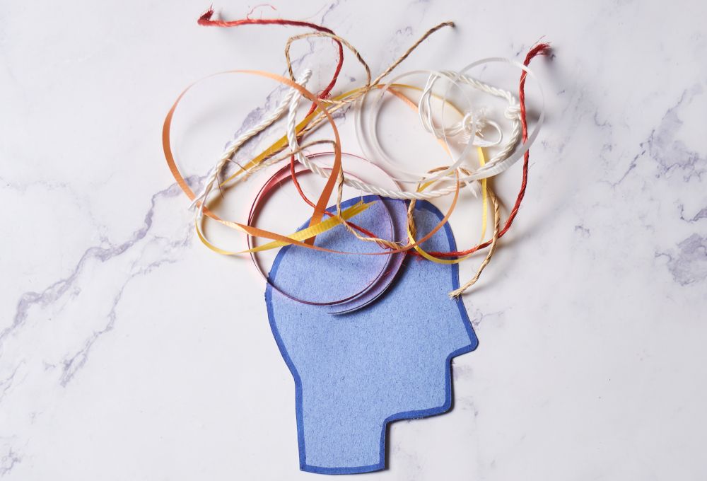 Dibujo de una cabeza con hilos en la parte del cerebro. Imagen que representa ansiedad y lio en la cabeza.