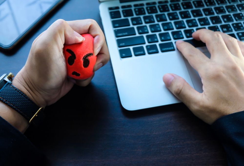 Primer plano de una persona trabajando en un portátil y en una de sus manos con una pelota anti estrés.
